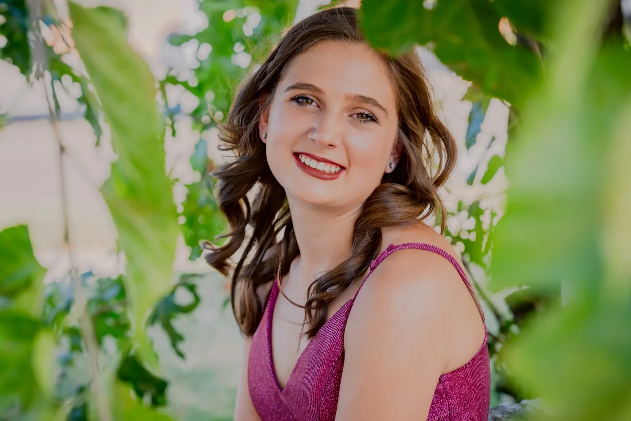 A close portrait through leaves, smiling