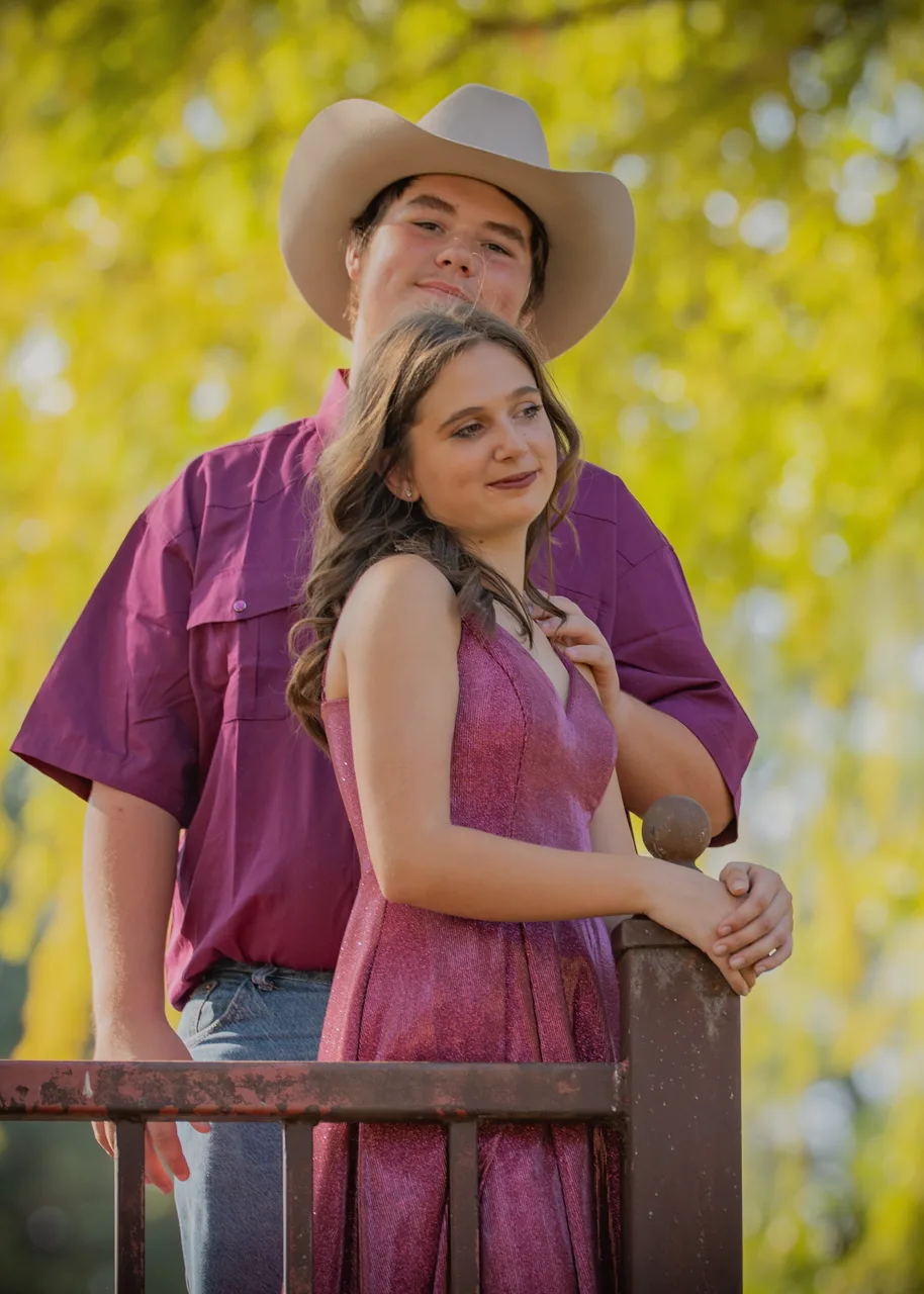 A couple standing on a bridge with yellow leaves behind them