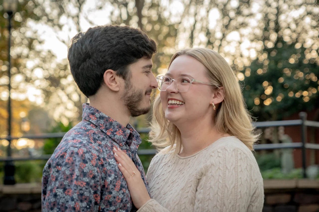A newly engaged couple laughing face to face